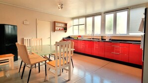 Una cocina moderna con armarios rojos, una mesa de comedor de vidrio y sillas blancas.