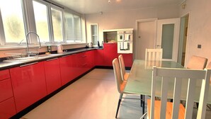 Una cocina moderna con armarios rojos, una mesa de comedor de vidrio y una silla blanca.