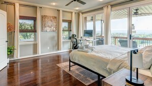 Un dormitorio amplio con una cama grande, un escritorio con computadora y vistas al exterior.