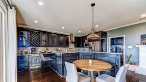 Una cocina moderna con armarios oscuros, una isla central y una mesa redonda de madera con sillas.