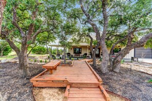 A wooden deck leading to a covered patio area with outdoor seating. - Modern Farmhouse w/ Hill Country Views, EV, Wineries, Large Patio (Dripping Springs)