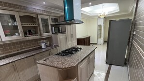Une cuisine moderne dotée de plans de travail en granit, d’un îlot central avec une plaque de cuisson et d’un four à micro-ondes placé au-dessus des placards.