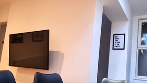Un salón de conferencias con una mesa de madera, sillas, un televisor de pantalla plana y un tragaluz en el techo.