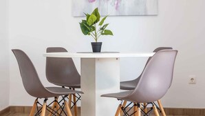 A dining area with a white table, four grey chairs, and a potted plant. - Holiday home with terrace near the sea (Šilo)