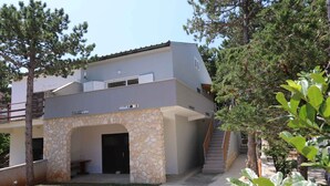 A modern two-story house with a stone facade, a covered outdoor seating area, and a staircase leading to the upper floor. - Holiday home with terrace near the sea (Šilo)