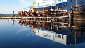 Restaurante à beira-mar com área externa e reflexo na água.
