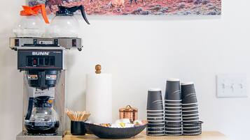A coffee station with a Bunn coffee maker, disposable cups, and a Taizo tea set.