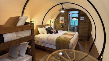 Una habitación tipo tienda de campaña, acogedora y circular, con literas y una mesa redonda de cristal.