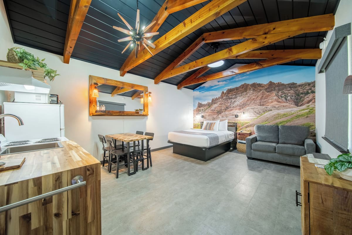 A modern interior with a kitchen, dining area, and a bedroom with a mountain mural.
