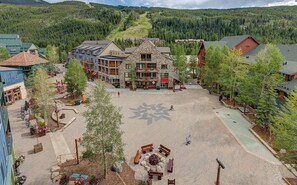 A resort with a central courtyard, stone buildings, and a mountainous backdrop.