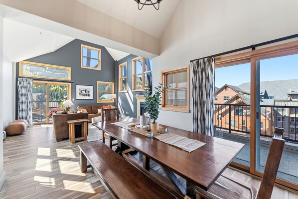 A spacious living area with a large wooden dining table, a sofa, and a fireplace.