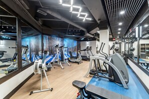 A gym with multiple treadmills, ellipticals, and a mirrored wall.
