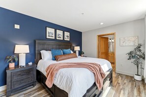 A bedroom with a bed, nightstands, a dresser, a wooden door, and a potted plant. - The Baldwin - Luxury Penthouse in the Heart of Keystone - Ski In/Out• $0 Cleaning Fee (Keystone)