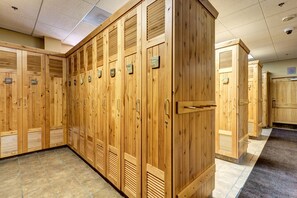 A row of wooden lockers with numbered tags, a tiled floor, and a ceiling with recessed lighting.