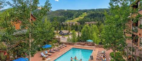 A pool area with multiple swimming pools, lounge chairs, and umbrellas.