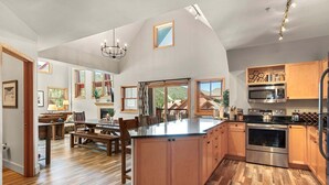 A spacious kitchen with wooden cabinets, a large island, and a view of the outdoors. - The Baldwin - Luxury Penthouse in the Heart of Keystone - Ski In/Out• $0 Cleaning Fee (Keystone)