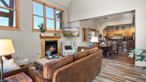 A spacious living area with a fireplace, a sofa, a television, and a kitchen in the background. - The Baldwin - Luxury Penthouse in the Heart of Keystone - Ski In/Out• $0 Cleaning Fee (Keystone)