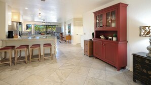 Eine geräumige Küche mit Kochinsel, Barhocker, einem roten Schrank und Deckenventilator.