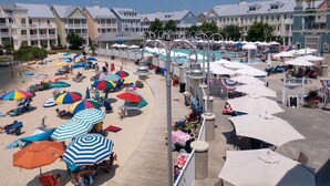A beachside resort with a pool, beach umbrellas, and lounge chairs.