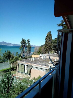 A view of a building with a rooftop terrace overlooking a body of water and mountains.