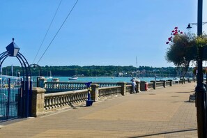 A waterfront promenade with a stone balustrade, a metal gate, and a row of street lamps. - Mulberry Cottage Coastal Holiday Home (Cowes)