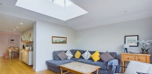 A living room with a grey sofa, a wooden coffee table, and a dining area with a chair and table.