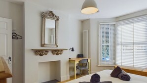 A bedroom with a bed, a desk, a chair, a mirror, and a window with blinds. - Blackberry Cottage Bembridge Accessible Coastal Holiday Home (Bembridge)