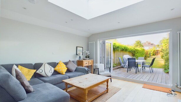 A spacious living room with a grey sofa, a wooden coffee table, and a view of the outdoor patio area. - Blackberry Cottage Bembridge Accessible Coastal Holiday Home (Bembridge)