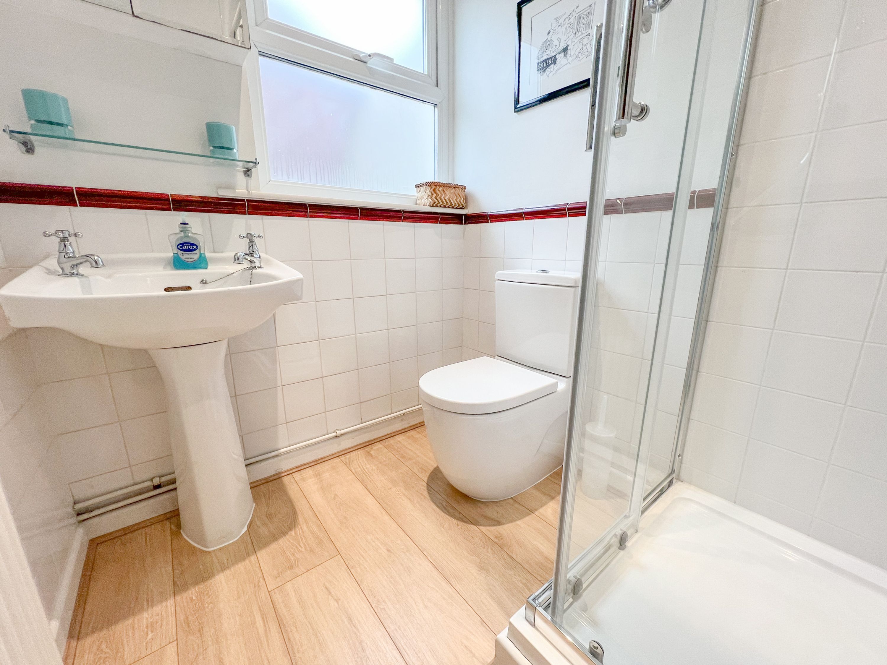 A bathroom with a white sink, a toilet, and a glass shower enclosure.