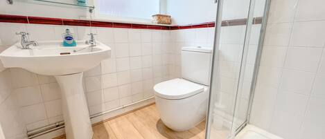 A bathroom with a white sink, a toilet, and a glass shower enclosure.