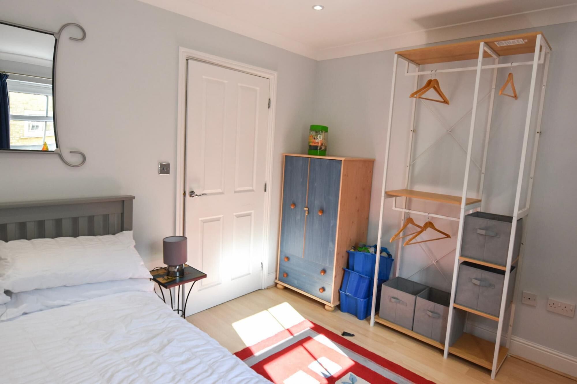 Une chambre à coucher comprenant un lit, une armoire et une étagère avec des cintres.