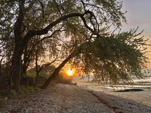 Un sentier de gravier menant à une plage, avec un coucher de soleil en arrière-plan.