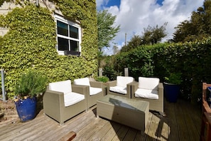 An outdoor patio with wicker furniture and a wooden deck. - Solent Landing No 16 Beach Retreat (Bembridge)