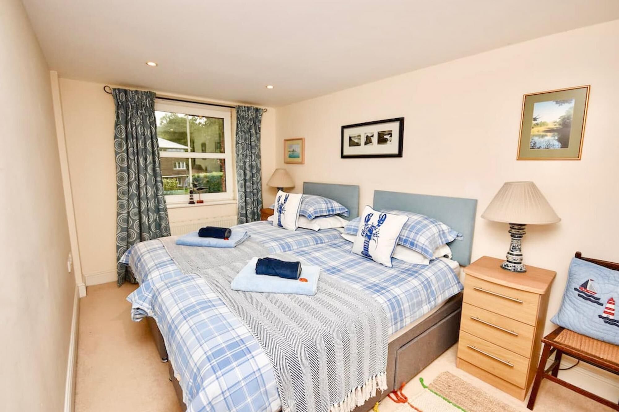 A bedroom with a double bed, two bedside tables, a nightstand, a lamp, and a framed picture on the wall.