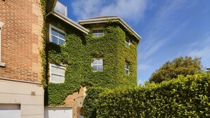 A two-story building with a brick facade partially covered in green ivy. - Solent Landing No 16 Beach Retreat (Bembridge)