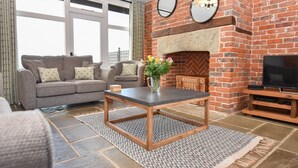 A living room with a brick fireplace, a sofa, a coffee table, and a television.
