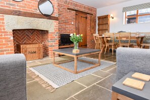 Ein gemütliches Wohnzimmer mit Kamin, Fernseher und Essbereich mit Holzmöbeln.
