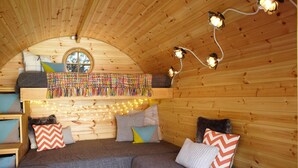 A cozy, wooden interior with a curved ceiling, a bed with colorful pillows, and string lights. - Gothic Cottage Hot Tub Fire Pit Pizza Oven Gas Bbq (Ryde)