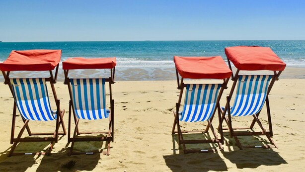 Four beach chairs with red canopies and blue-striped cushions on a sandy beach. - Gothic Cottage Hot Tub Fire Pit Pizza Oven Gas Bbq (Ryde)