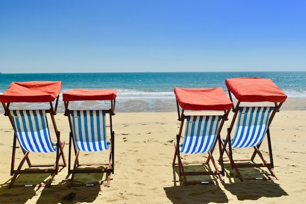 Relax in comfort with ocean views from our beach chairs, each equipped with a canopy and striped cushion.