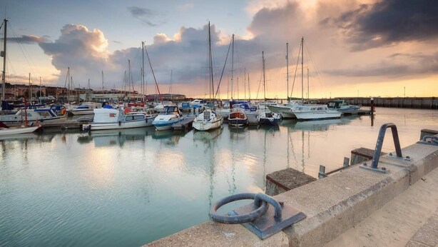 A marina with multiple boats docked at calm water, a concrete walkway, and a cloudy sky. - Queens Mews a Coastal Holiday Home (Ryde)
