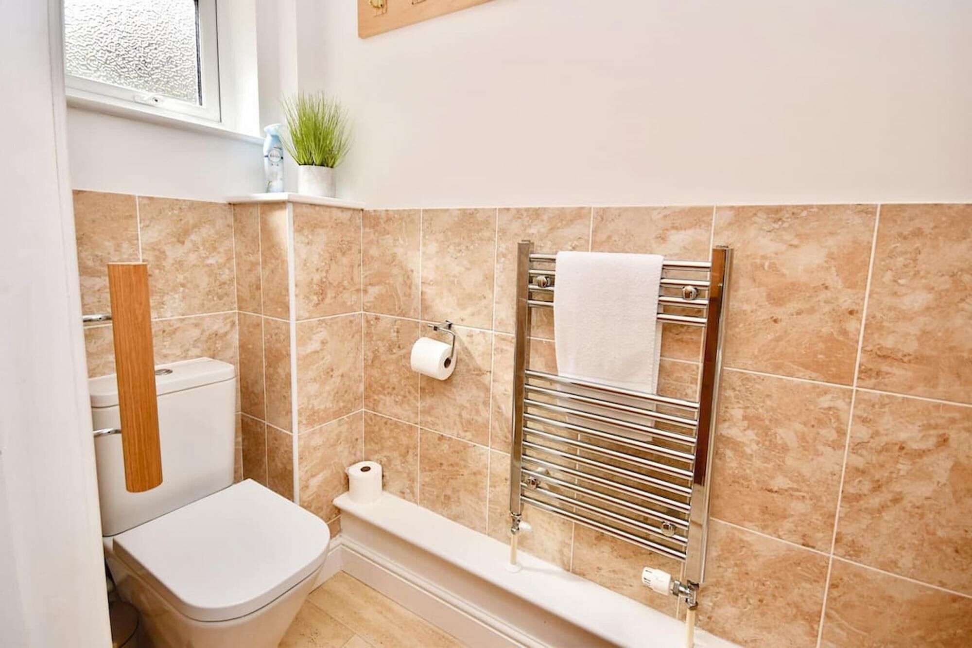 A bathroom with a toilet, a towel rack, and a shower area.