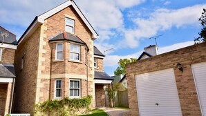 A two-story brick house with a garage, a small front yard, and a clear sky. - Queens Mews a Coastal Holiday Home (Ryde)
