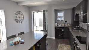 A modern kitchen with a large island, built-in appliances, and a view to the outside. - Seaside Cottage in Ryde (Ryde)