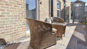 A patio with wicker furniture and a brick wall. - Seaside Cottage in Ryde (Ryde)