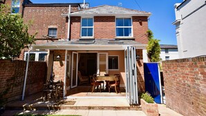Une maison à deux étages dotée d’un patio couvert, d’une façade en briques et d’une cheminée visible.
