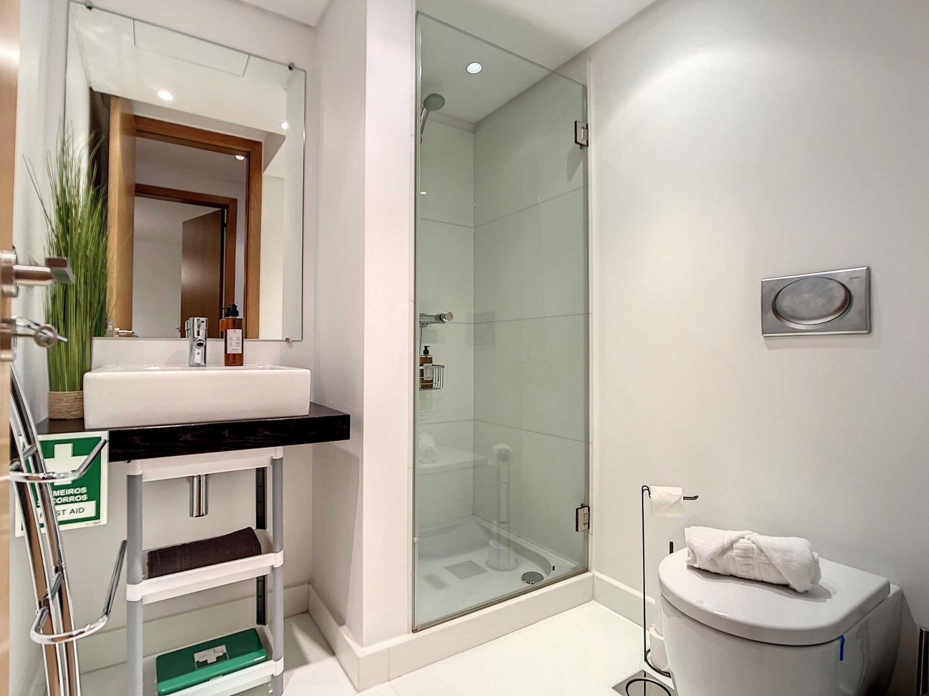 Un bagno moderno con box doccia in vetro, lavandino bianco e water.
