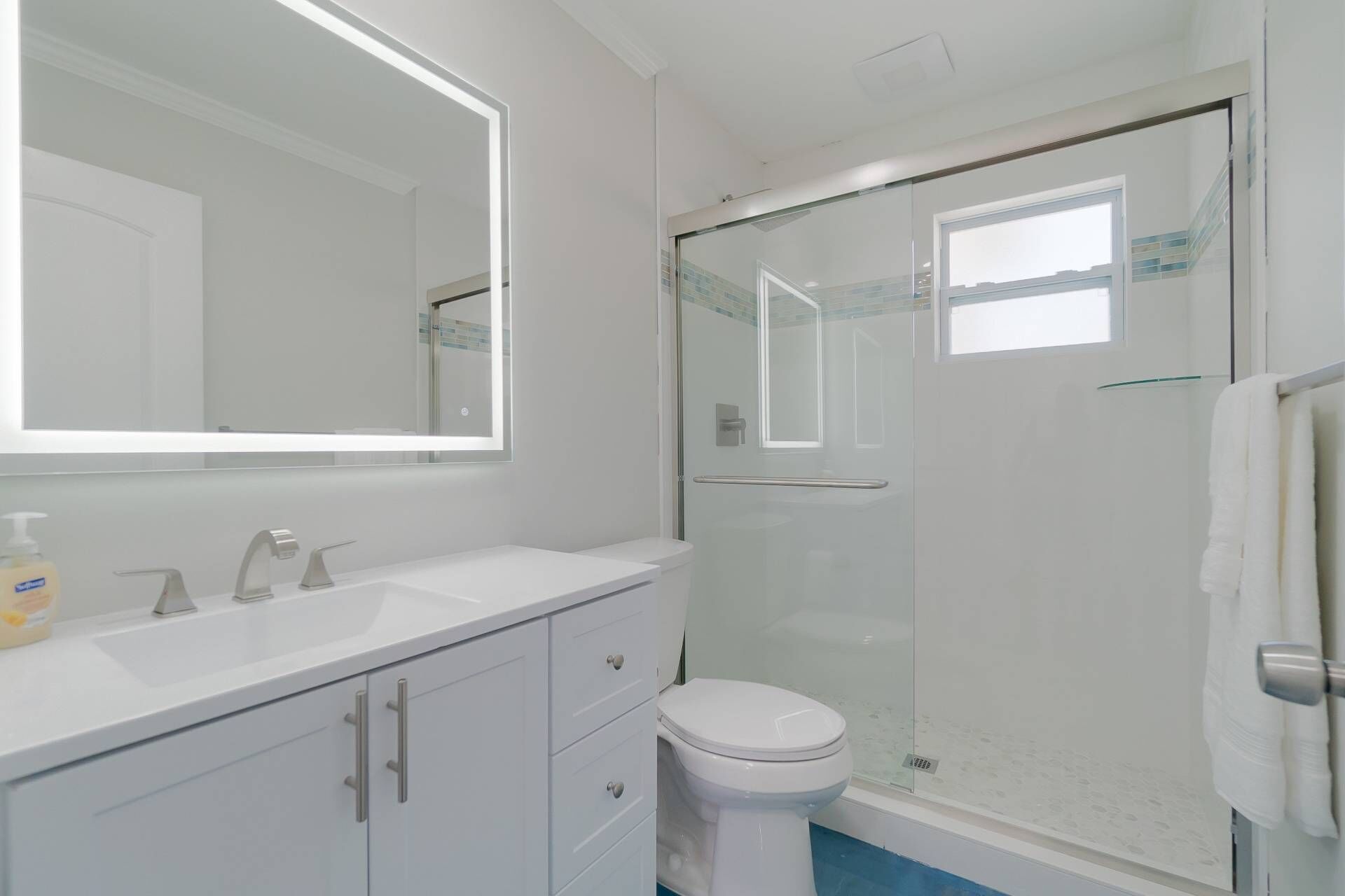 Un bagno con un mobile lavabo bianco, uno specchio grande, un water e una cabina doccia in vetro.