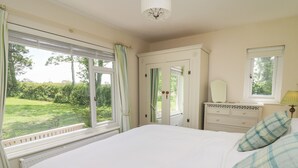 Ein Schlafzimmer mit einem großen Bett, einem Schminktisch, einem Spiegel und einem Fenster mit Vorhängen.