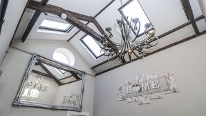 A room with a high ceiling, skylights, a chandelier, a large mirror, and a wall with a 'LOVE' decoration.